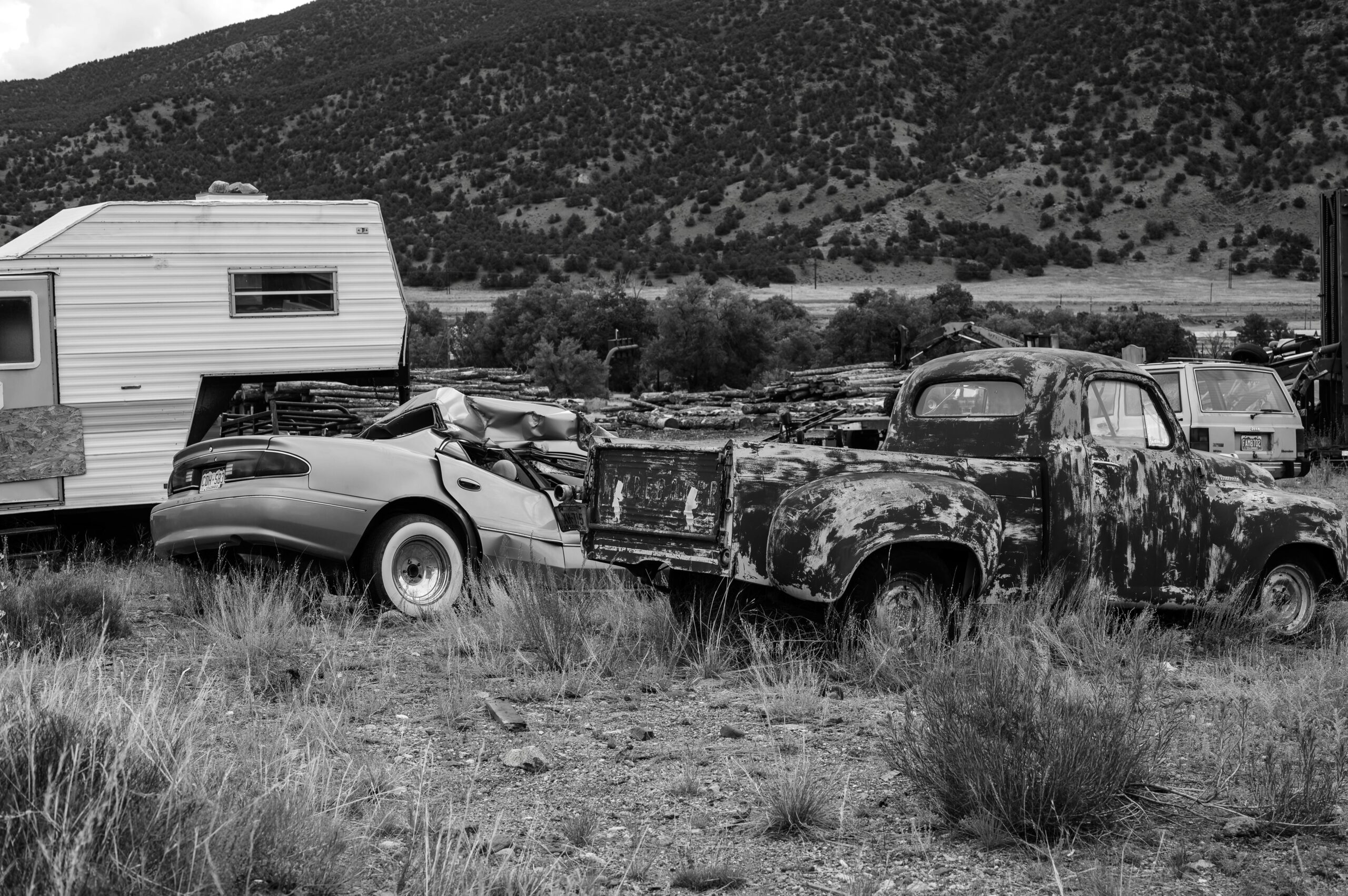 pexels-photo-12697981-12697981 Black and white photo of rusty abandoned vehicles and camper in rural setting.